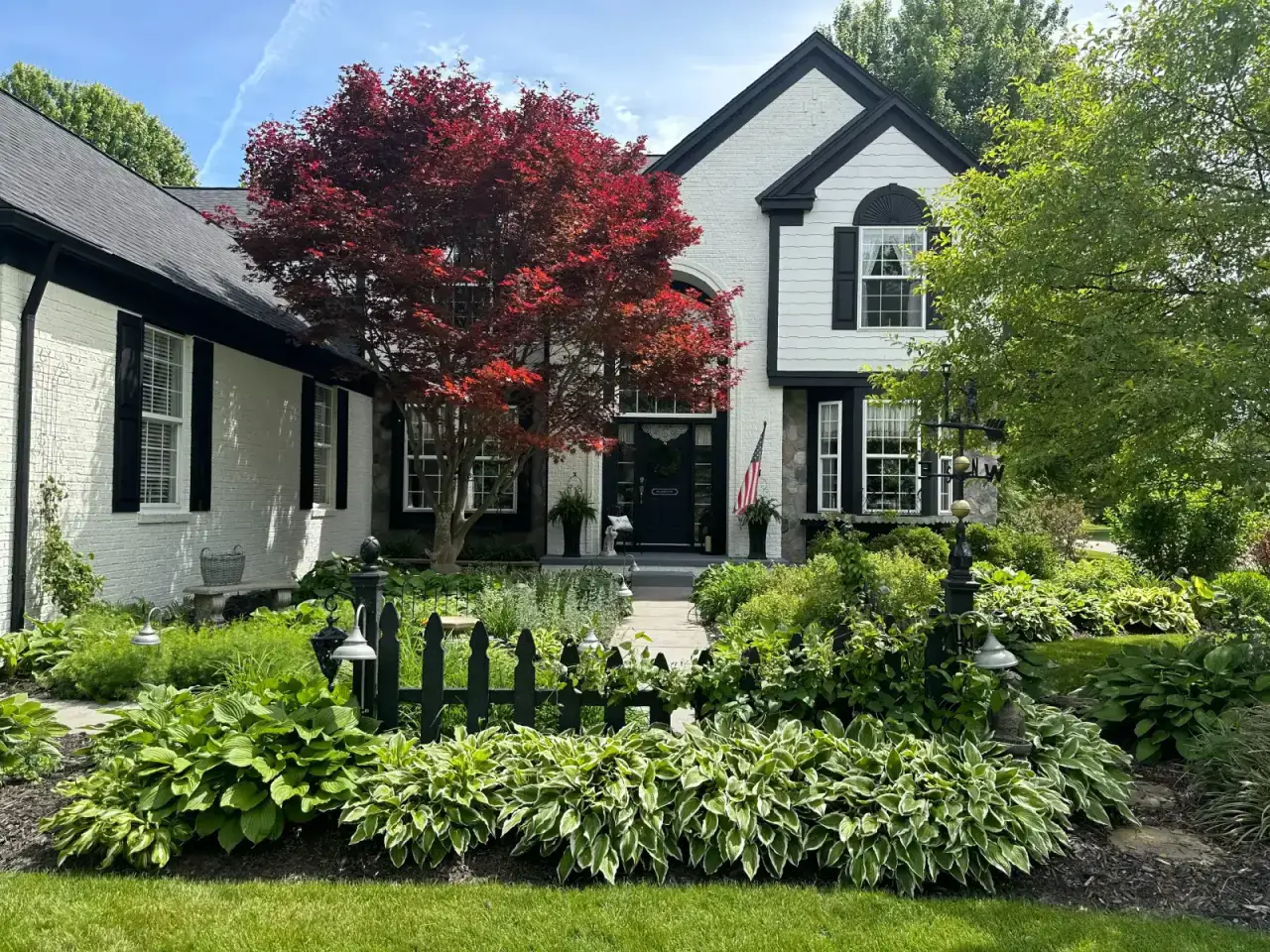 After — White brick two-storey home exterior with black shutters after repainting