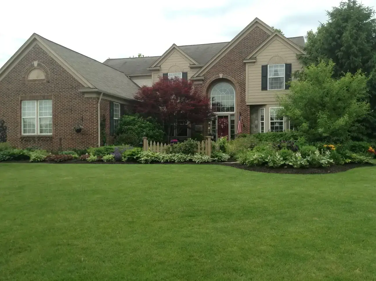 Before — White brick two-storey home exterior with black shutters after repainting