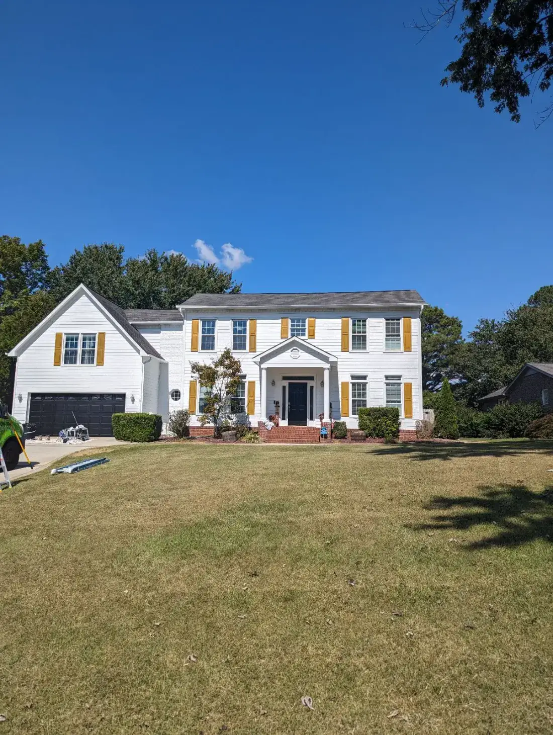 After — Two-storey home exterior repainted white with gold shutters