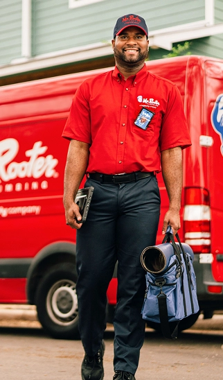 Plumbing technician standing in front of a service van