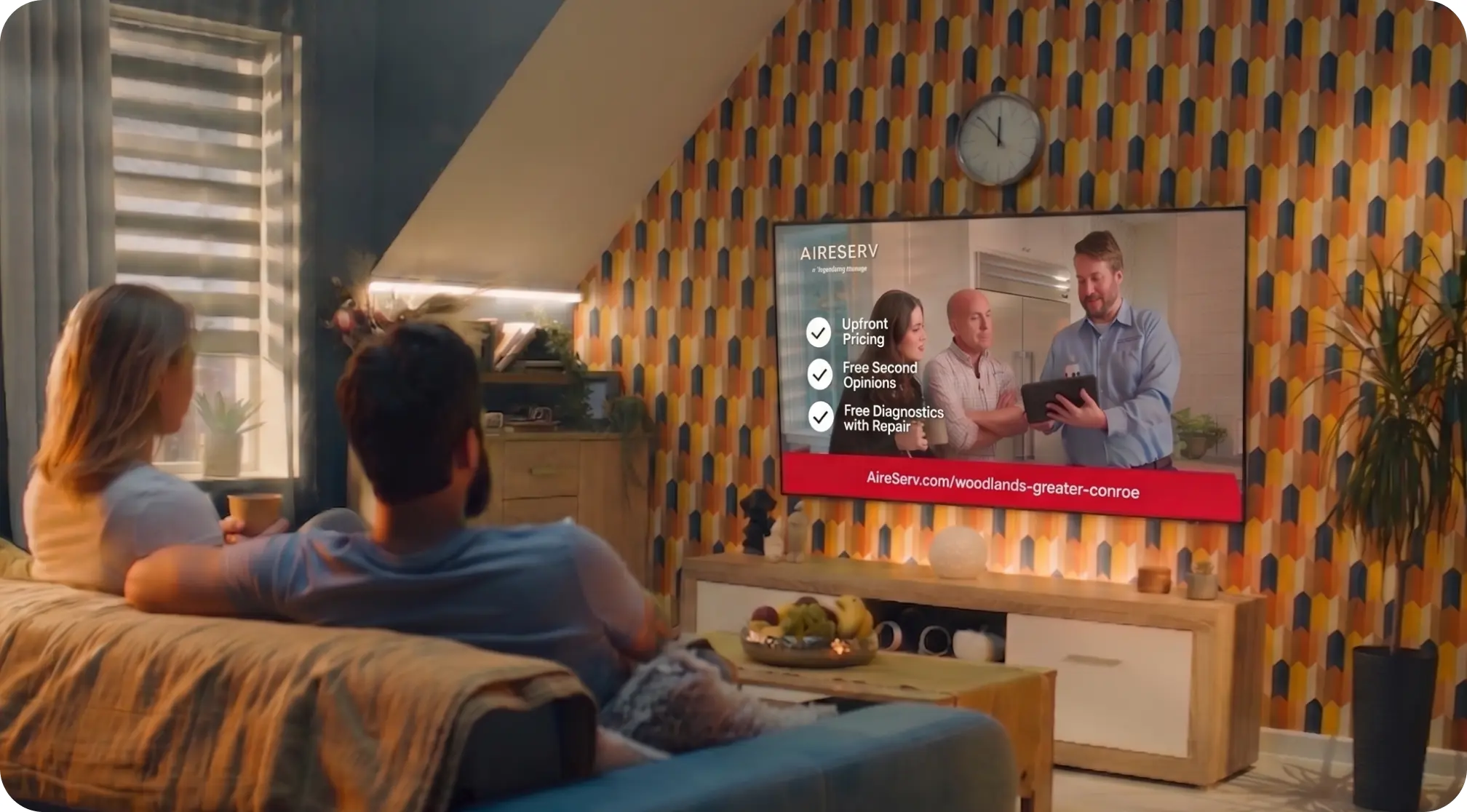 Family watching a local TV commercial in a living room