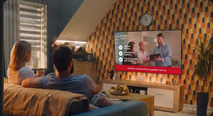 Family watching a local TV commercial in a living room